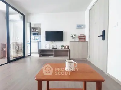 Modern living room with minimalist decor and wooden furniture, featuring a TV and glass partition.