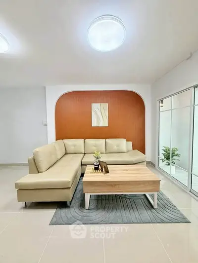 Modern living room with stylish beige sectional sofa and wooden coffee table, featuring elegant decor and bright lighting.