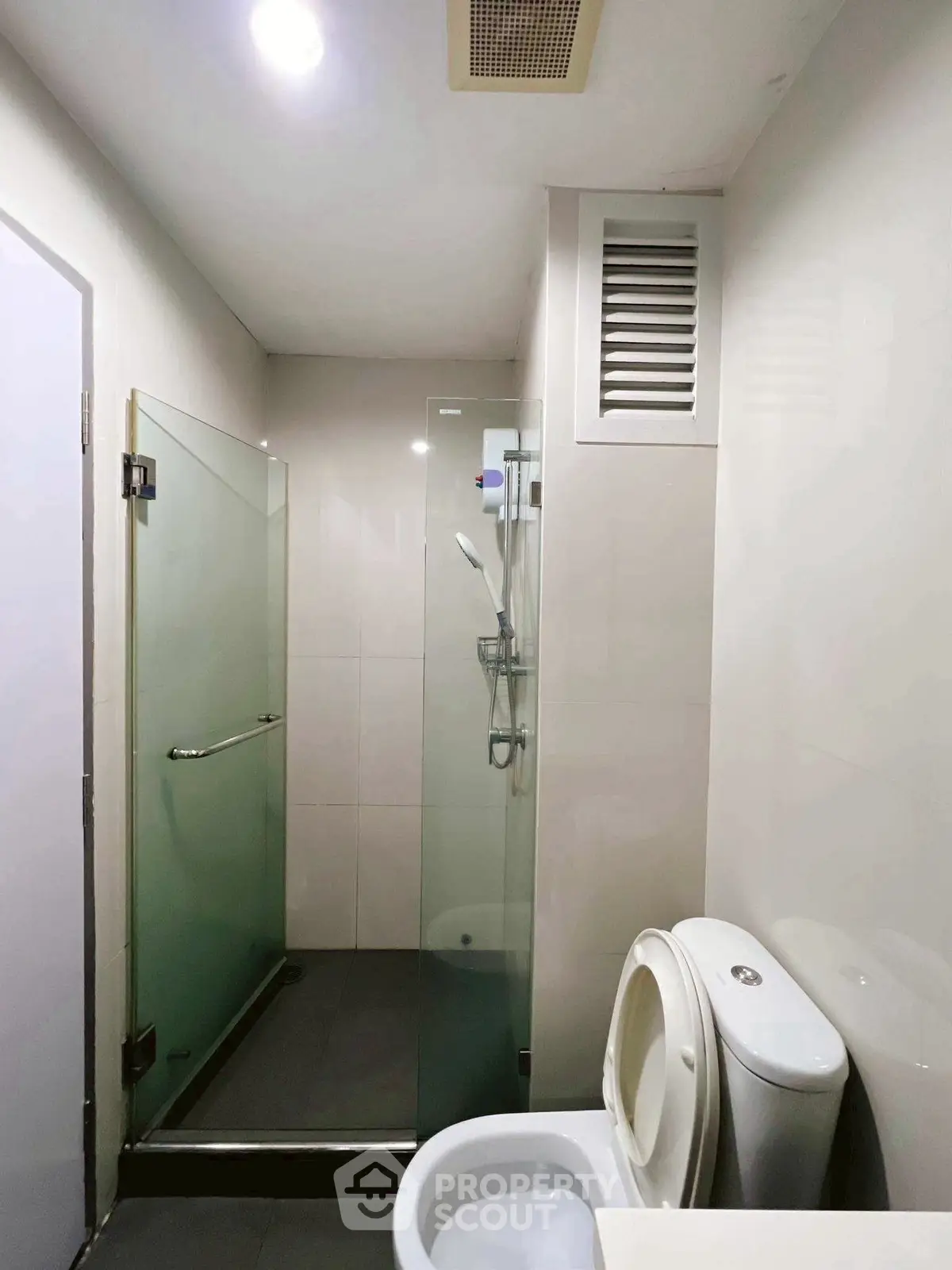 Modern bathroom with glass shower and sleek fixtures in contemporary apartment.