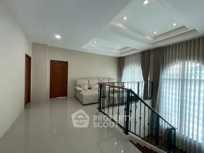 Spacious living area with elegant staircase and cozy seating, featuring large windows and modern ceiling design.