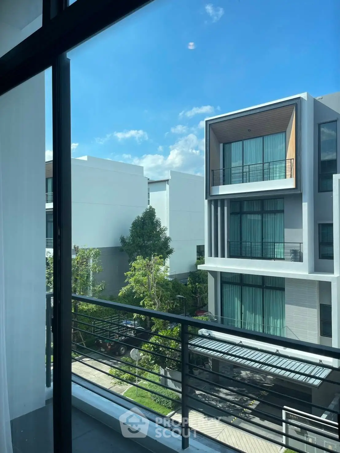 Modern residential building with large windows and balconies, offering a serene view of the neighborhood.