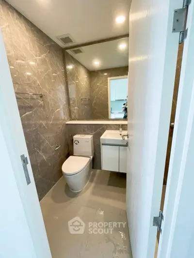 Modern bathroom with sleek design and marble walls in a contemporary apartment.