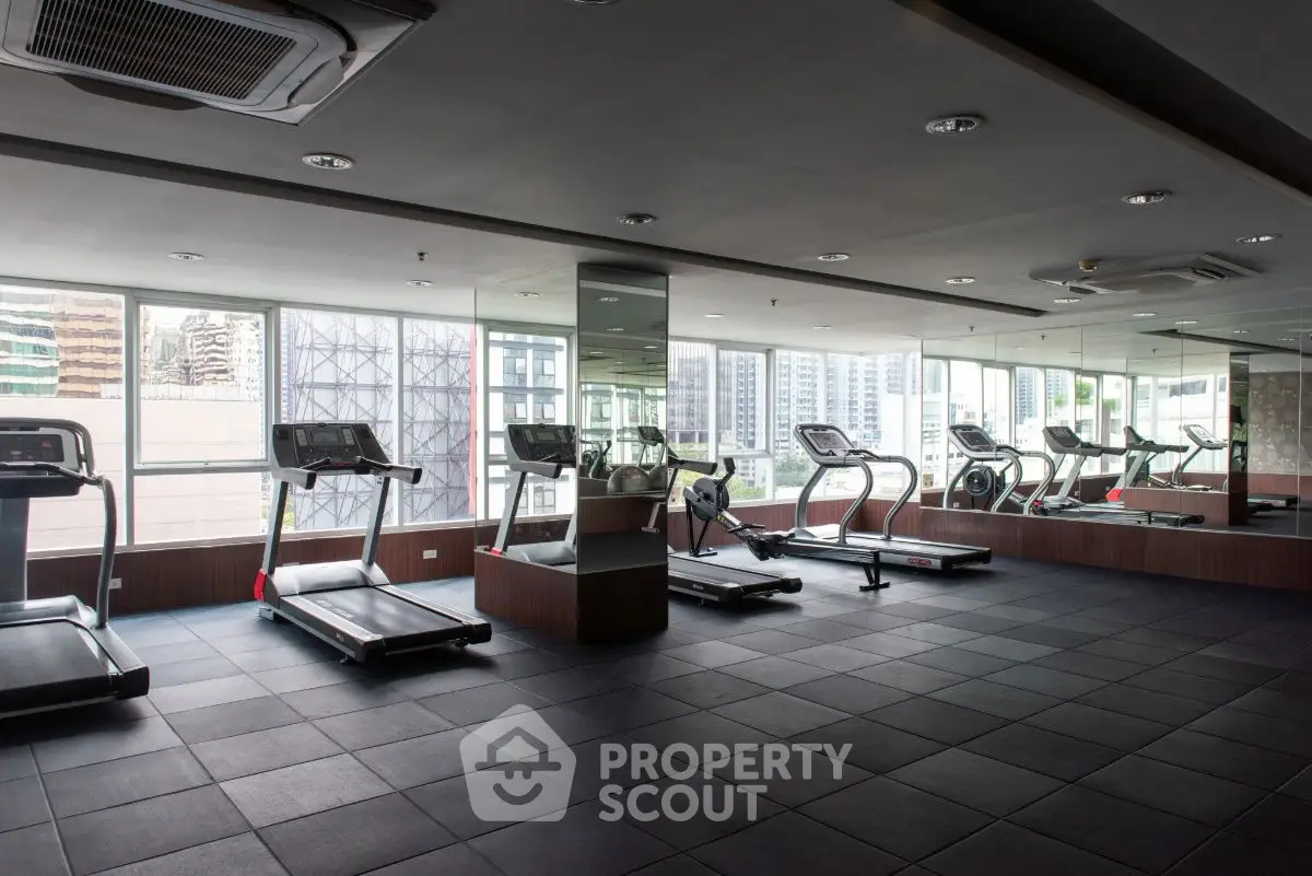 Modern gym with treadmills and city view in luxury apartment building.