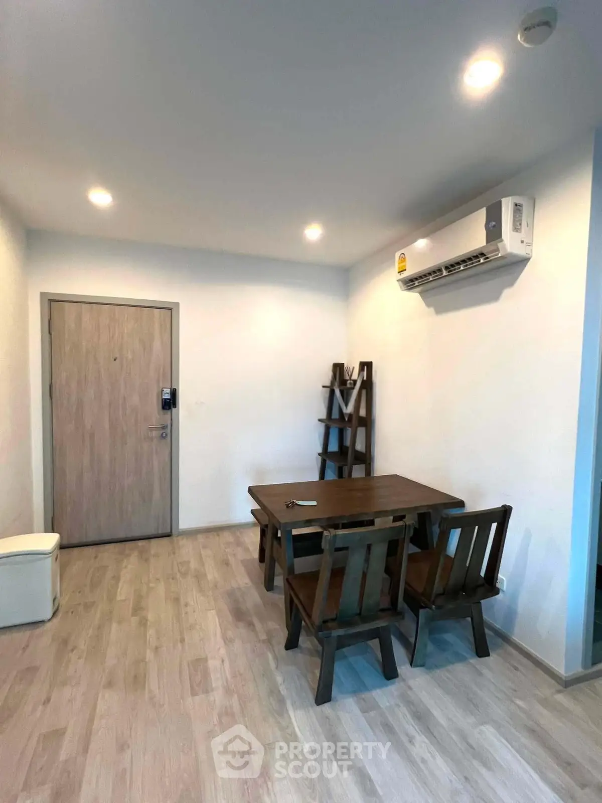 Cozy dining area with wooden table and chairs, featuring modern air conditioning and minimalist decor.