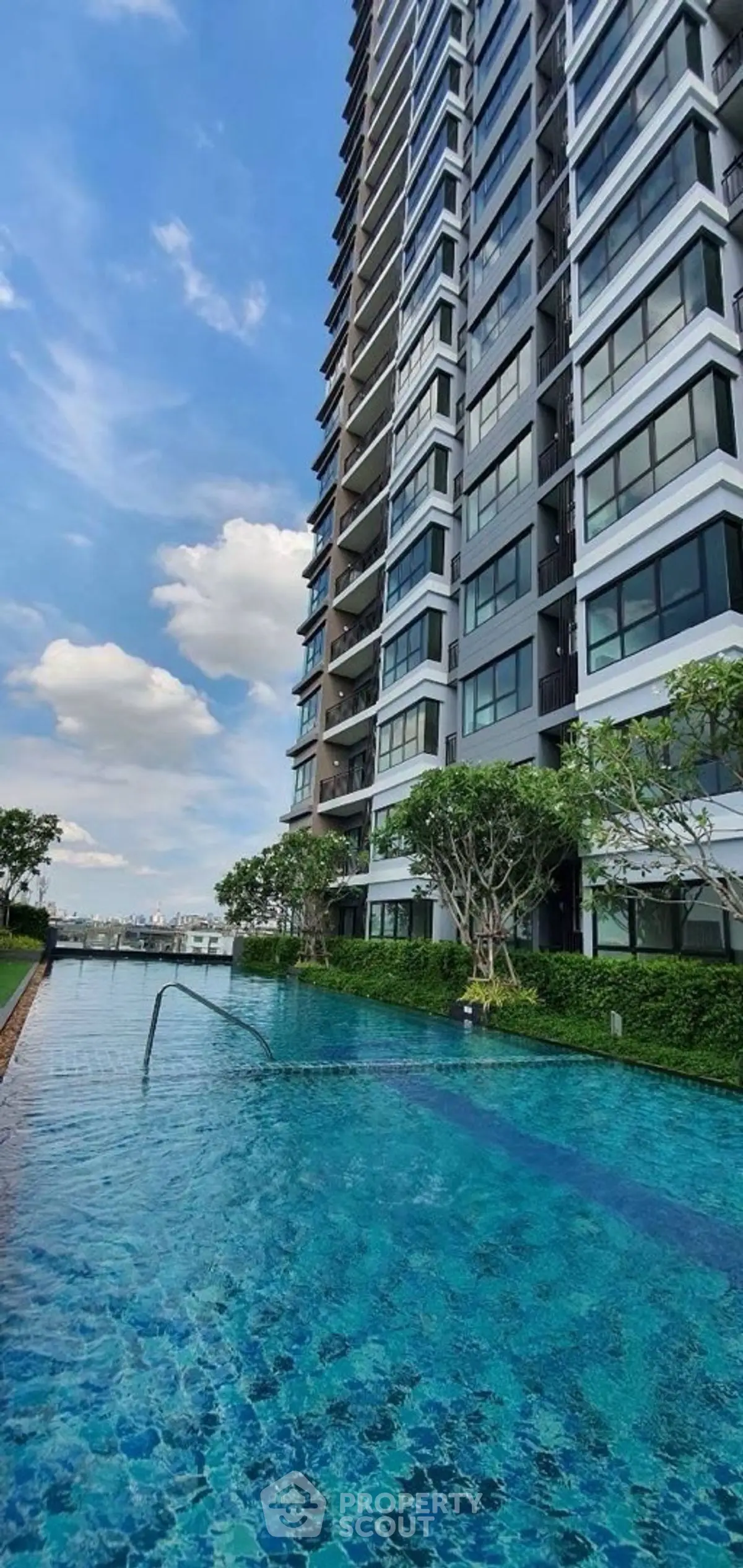 Luxurious high-rise building with stunning pool and lush greenery, perfect for modern living.