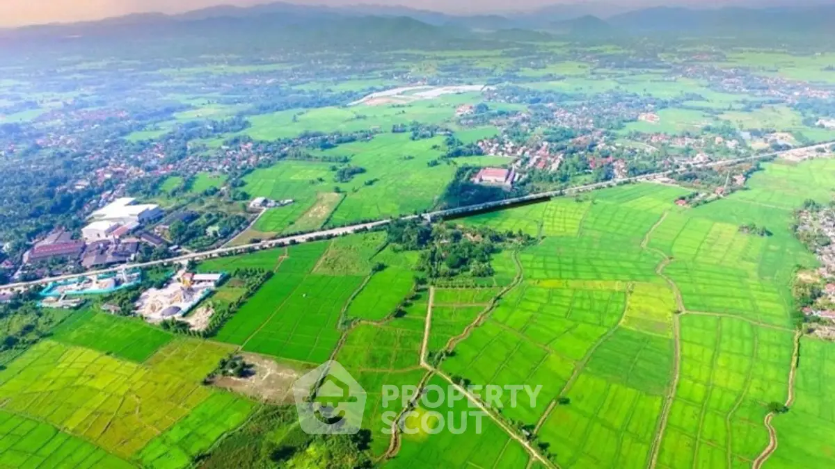 Aerial view of expansive green fields and distant mountains, showcasing vast agricultural land.