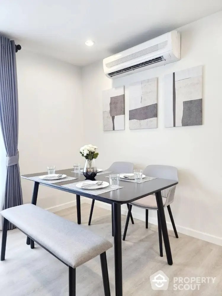 Modern dining area with sleek table, stylish chairs, and wall art in a bright interior setting.