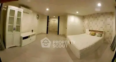 Spacious bedroom with modern decor and ample lighting, featuring a comfortable bed and stylish furnishings.