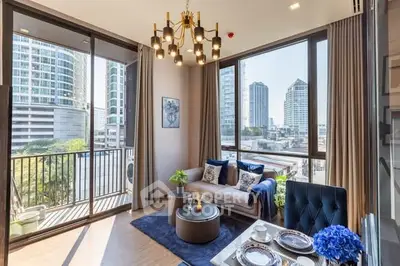 Modern living room with large windows and city view, featuring elegant decor and cozy seating area.