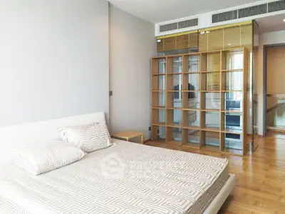 Spacious modern bedroom with wooden flooring and stylish shelving unit