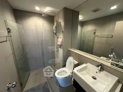 Modern bathroom with glass shower and sleek fixtures in contemporary apartment.