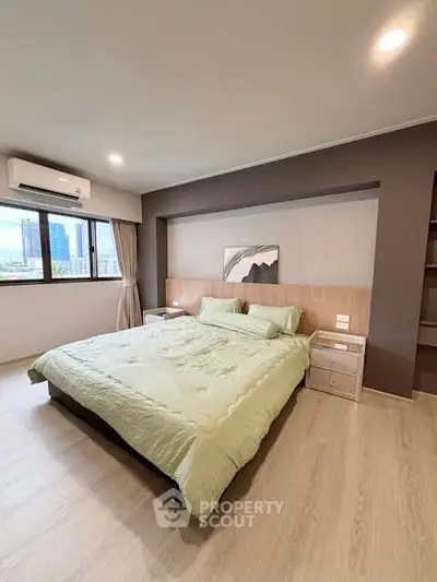 Spacious modern bedroom with large window and stylish decor in urban apartment.