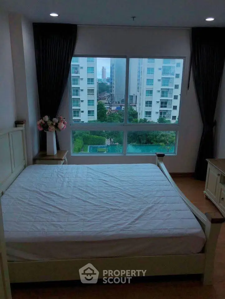 Spacious bedroom with large window offering stunning city views in modern apartment.