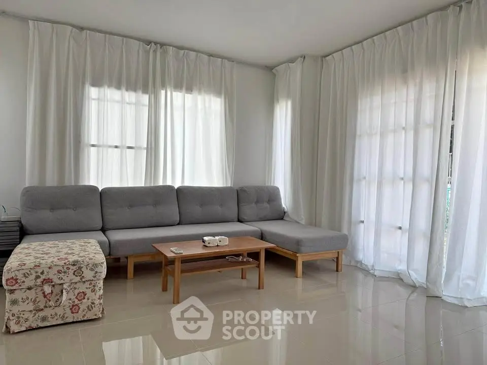 Spacious living room with modern gray sectional sofa and elegant white curtains
