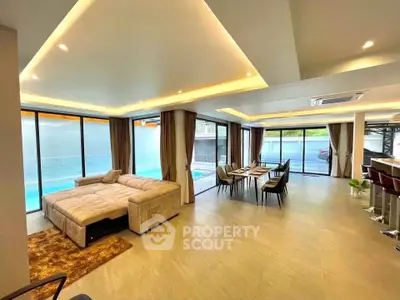 Luxurious open-plan living room with pool view and modern furnishings.