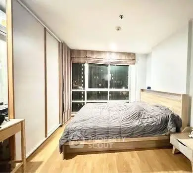 Spacious bedroom with large windows and modern decor in a high-rise apartment.