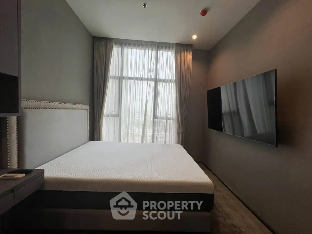 Modern bedroom with large window and wall-mounted TV in a stylish apartment.