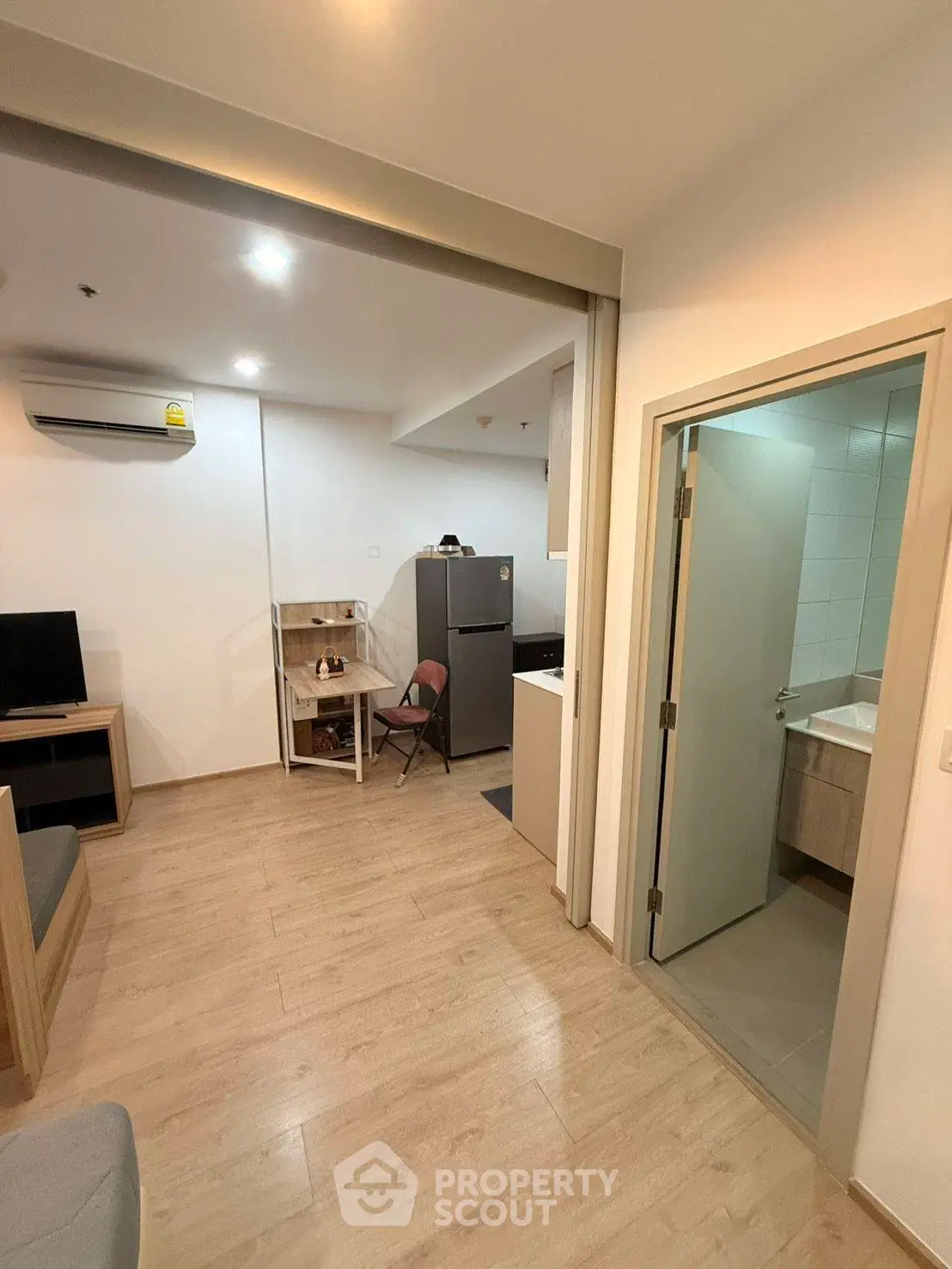 Modern apartment interior with open living area and kitchen, featuring wooden flooring and contemporary design.