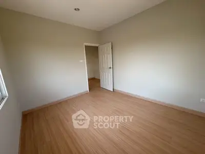 Spacious empty room with wooden flooring and neutral walls, ready for customization.