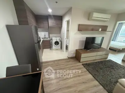 Modern open-plan living room with kitchen, featuring sleek appliances and stylish decor.