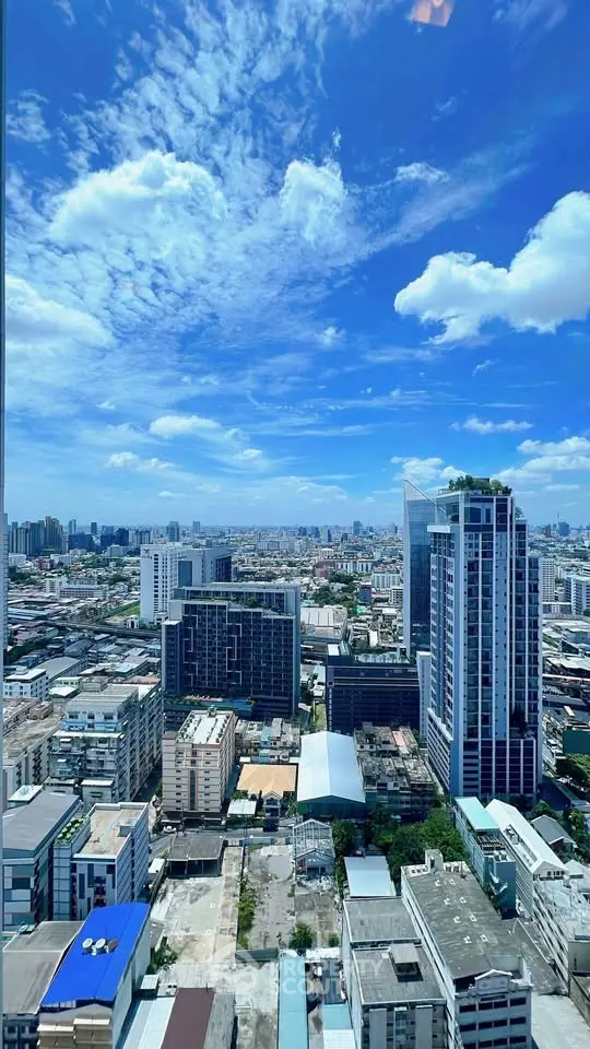 Stunning cityscape view from a high-rise building showcasing urban skyline under a vibrant blue sky.