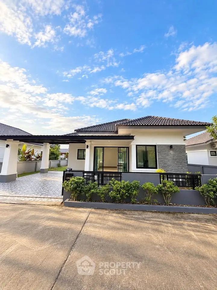 Charming modern bungalow with lush garden and spacious driveway under a clear blue sky.