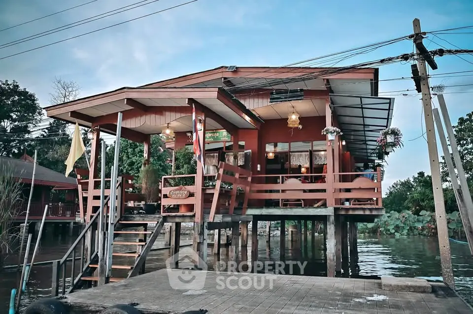 Charming waterfront stilt house with rustic wooden design and lush greenery.