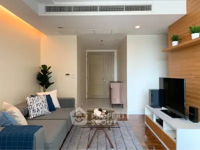 Modern living room with stylish decor and natural light, featuring a cozy sofa and entertainment center.