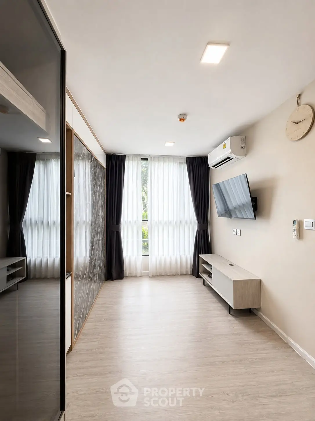 Modern living room with large window, wall-mounted TV, and sleek air conditioning unit.
