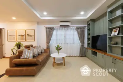 Elegant living room with modern decor, featuring a cozy leather sofa, stylish shelving, and a large flat-screen TV.