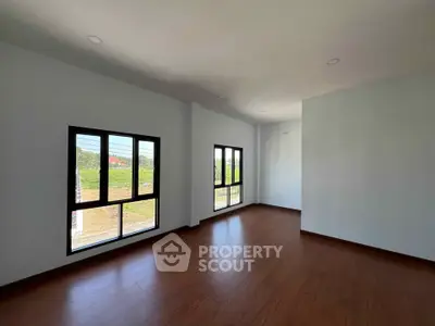Spacious empty room with large windows and wooden flooring, perfect for customization.