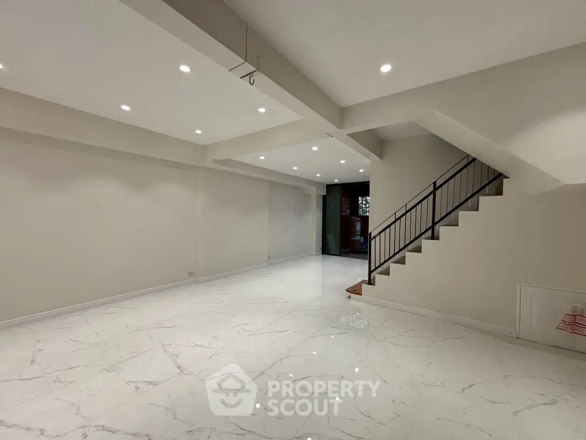 Spacious modern living room with elegant staircase and marble flooring