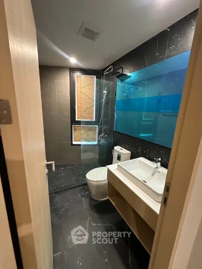 Modern bathroom with sleek black tiles and glass shower enclosure