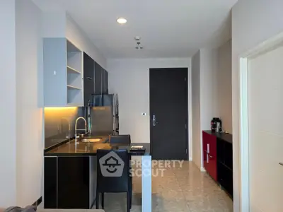Modern kitchen with sleek black cabinets and stainless steel appliances in a stylish apartment.