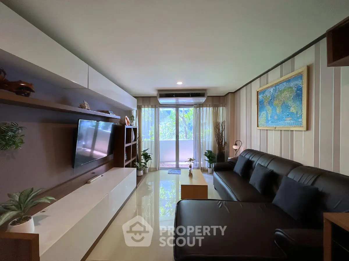 Modern living room with sleek furniture and large window offering natural light and greenery view.