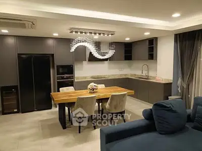 Modern kitchen with sleek design, featuring a wooden dining table and elegant lighting.