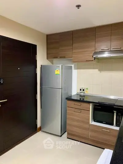 Modern kitchen with sleek wooden cabinets and stainless steel appliances in a cozy apartment.