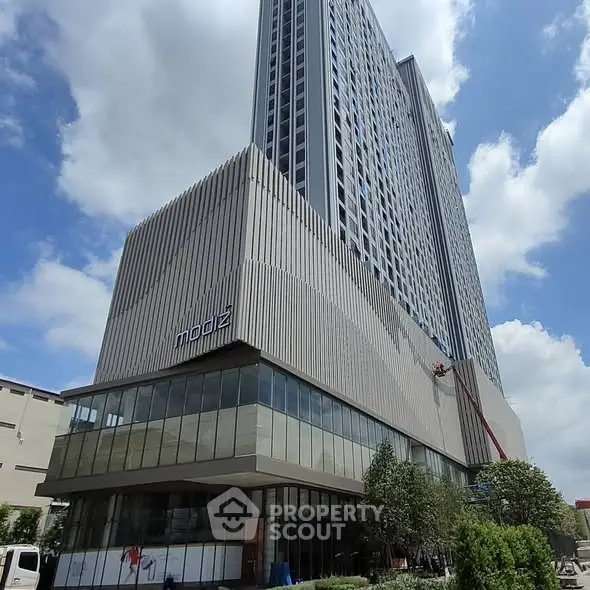 Modern high-rise building with sleek architecture and glass facade under a blue sky.