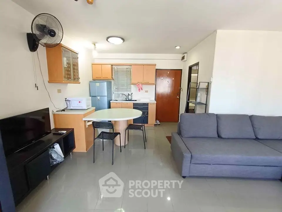 Modern open-plan living room with kitchen, featuring sleek furniture and appliances.
