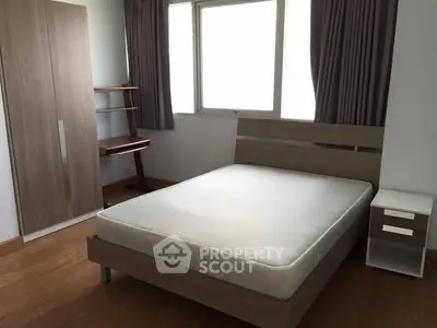 Modern bedroom with wooden furniture and large window for natural light.