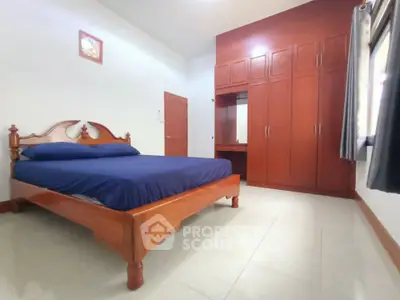 Spacious bedroom with wooden furniture and built-in wardrobe, perfect for comfort and style.