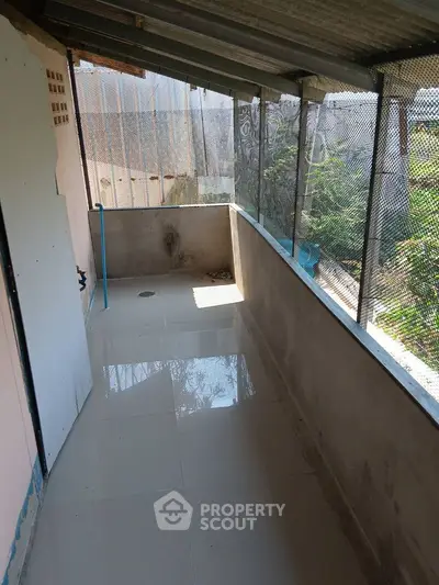 Spacious balcony with tiled flooring and partial enclosure, ideal for relaxation.