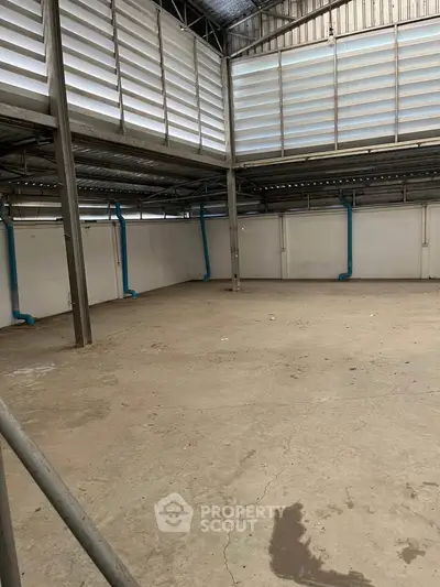 Spacious industrial warehouse with high ceilings and ample natural light, perfect for storage or manufacturing needs.