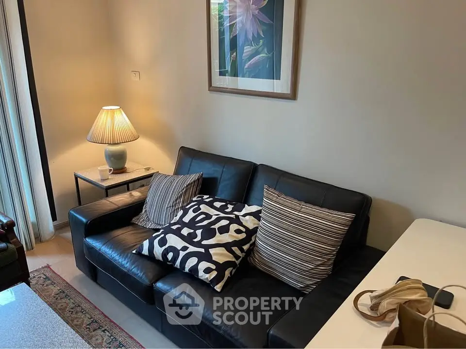 Cozy living room with stylish black leather sofa and decorative pillows, perfect for relaxation.