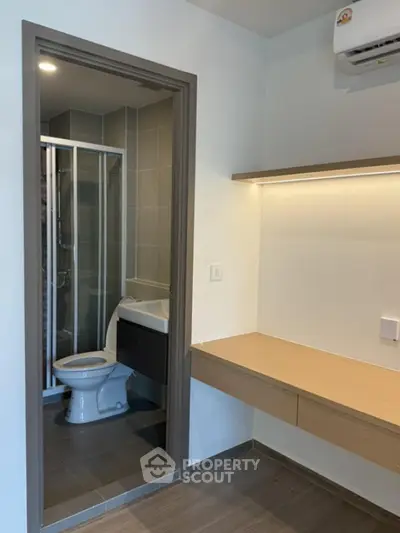 Modern bathroom with sleek design and adjacent workspace in a contemporary apartment.