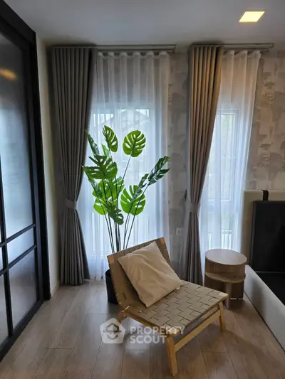 Stylish living room with modern chair, lush plant, and elegant curtains.