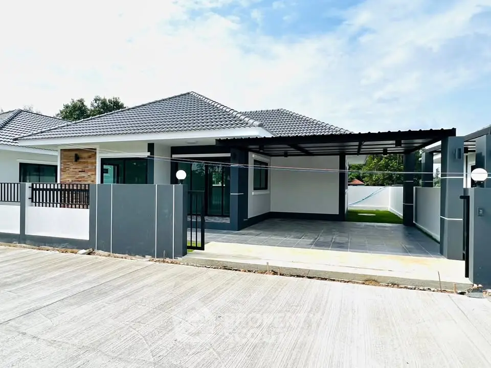 Modern single-story house with spacious driveway and sleek design.