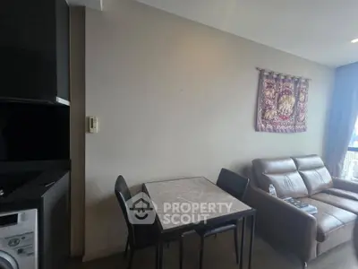 Modern living room with compact dining area and cozy seating, featuring a washing machine and stylish wall decor.