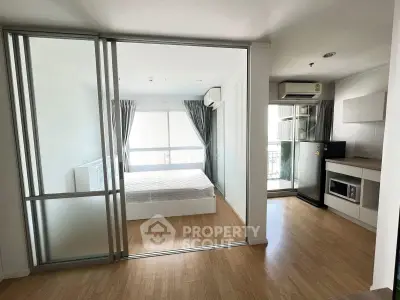 Modern studio apartment with glass partition, wooden flooring, and natural light.