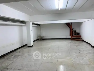 Spacious basement area with tiled flooring and staircase, ideal for storage or renovation.